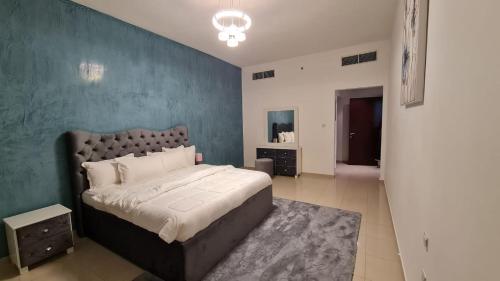 a bedroom with a large bed and a blue wall at Luxurious Private Beach & Pool, fully Furnished 1BR Apartment at Marjan Island Ras al khaimah in Ras al Khaimah
