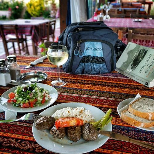 AkçapınarにあるTroia Pensionの食べ物の皿とワインのグラスが置かれたテーブル