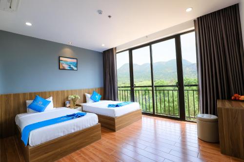 a hotel room with two beds and a large window at Havana Con Dao Hotel in Con Dao