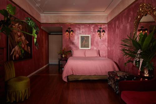 Dormitorio rosa con cama y silla en Eltham Hotel NSW, en Eltham