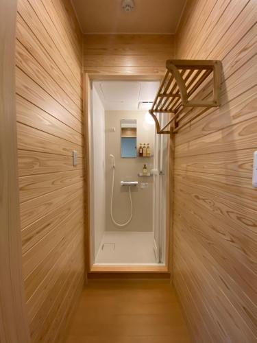 a walk in shower in a bathroom with wooden walls at AJITO Hostel & CafeBar in Shingu