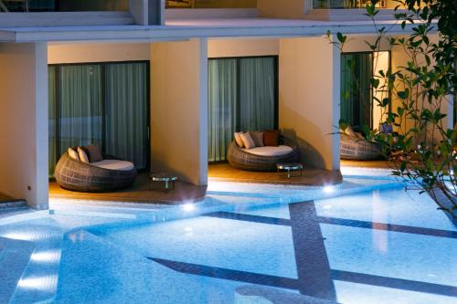 a hotel swimming pool with two lounges and chairs at The Signature Hotel Airport in Hat Yai