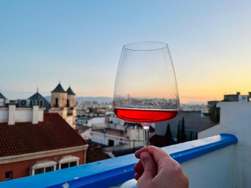 a person holding a glass of wine on a ledge at Charming home with private terrace,heart of Málaga in Málaga