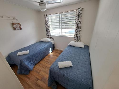 two beds in a room with a window at Castaways Moreton Island in Bulwer