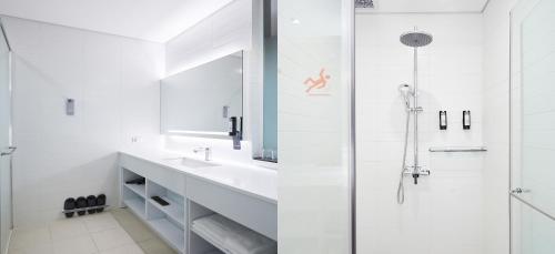 a white bathroom with a sink and a shower at Grand City Hotel Changwon in Changwon