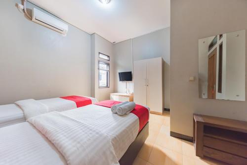 a bedroom with two beds and a tv in it at RedDoorz Syariah near Politeknik Negeri Bandung Campus in Bandung