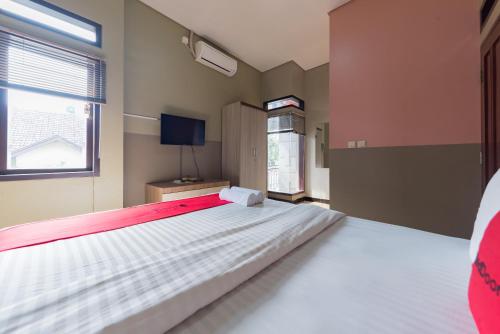 a bedroom with a large bed and a window at RedDoorz Syariah near Politeknik Negeri Bandung Campus in Bandung