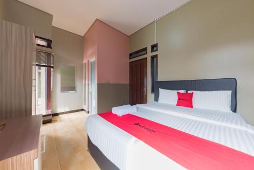 a bedroom with a large white bed with a red pillow at RedDoorz Syariah near Politeknik Negeri Bandung Campus in Bandung