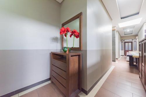 a hallway with a mirror and red flowers on a dresser at RedDoorz Syariah near Politeknik Negeri Bandung Campus in Bandung