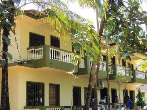 a yellow building with a balcony and palm trees at John's Highland Comfort (Guest House) in Majorda
