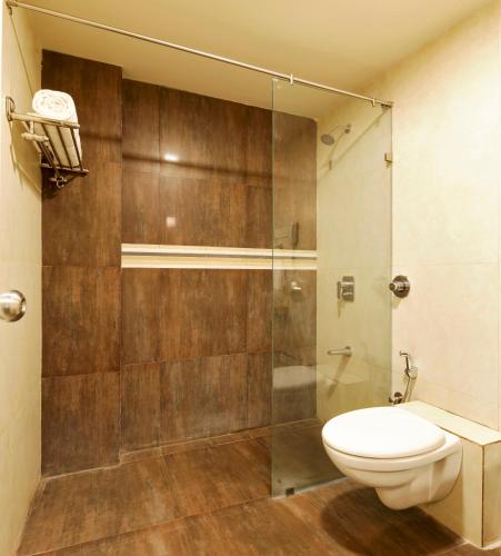 a bathroom with a toilet and a glass shower at Regenta Place Raysons Kolhapur in Kolhapur