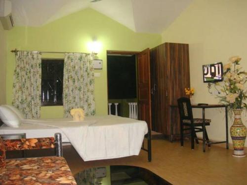 a room with a bed and a table and a chair at John's Highland Comfort (Guest House) in Majorda