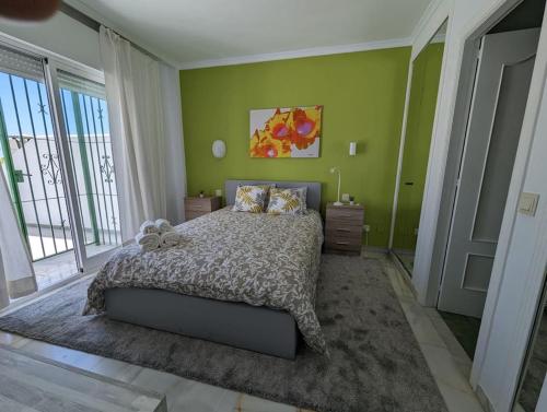 een slaapkamer met een bed en een groene muur bij Apartamento los Cocoteros in Santa Fe de los Boliches
