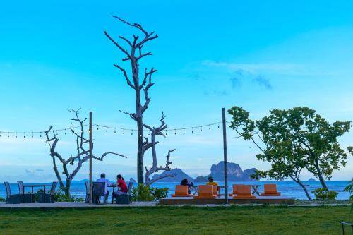 a group of people sitting on benches near the water at Tinidee Hideaway Tonsai Beach Krabi - SHA Extra Plus in Tonsai Beach