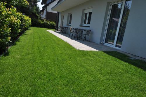 a lawn with chairs and tables on a house at APARTAMENTY POD ŻAGLAMI MIELENKO in Mielenko