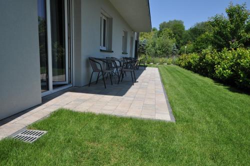 a patio with tables and chairs on the grass at APARTAMENTY POD ŻAGLAMI MIELENKO in Mielenko