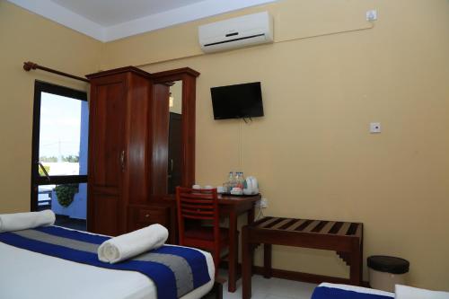 Habitación de hotel con cama, escritorio y TV. en PJ Hotels Jaffna, en Jaffna