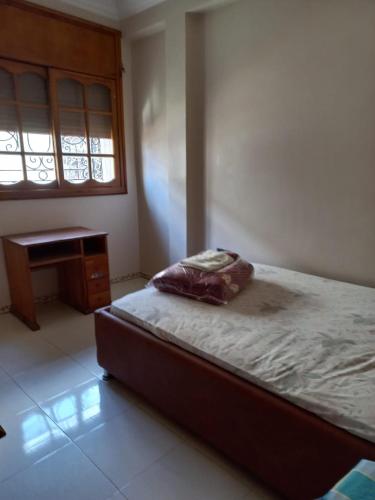 傑迪代的住宿－Apartment El Jadida，一间卧室配有一张床、一张书桌和一个窗户。