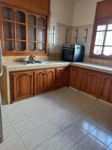 a kitchen with wooden cabinets and a tile floor at Apartment El Jadida in El Jadida