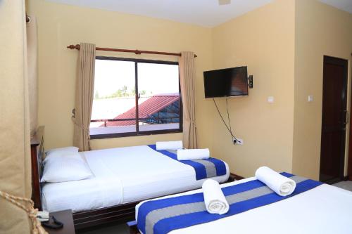 a hotel room with two beds and a window at PJ Hotels Jaffna in Jaffna