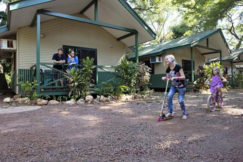 a young girl riding a scooter next to a house at Discovery Parks - Darwin in Darwin