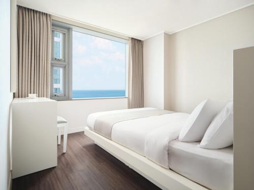 sypialnia z łóżkiem i dużym oknem w obiekcie Hanwha Resort Haeundae w Pusanie