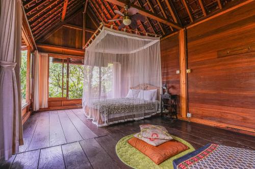a bedroom with a bed in a room with wooden walls at Sari Bamboo Bungalows in Ubud