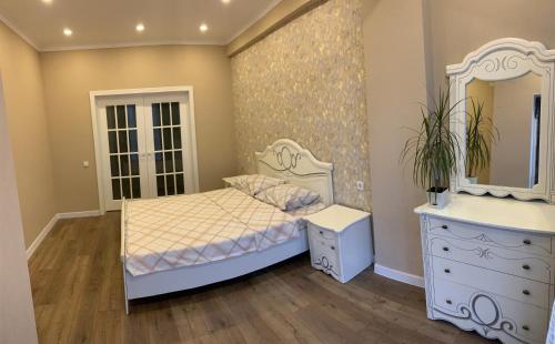 a bedroom with a bed and a dresser and a mirror at Апартаменты в центре города in Bishkek