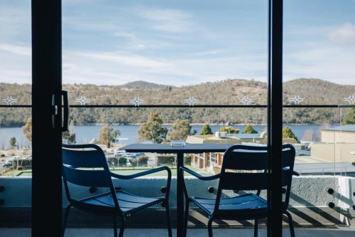 a table and chairs on a balcony with a view of a lake at Banjo Paterson Inn in Jindabyne