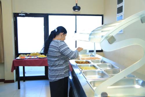 a woman is preparing food in a buffet at PJ Hotels Jaffna in Jaffna