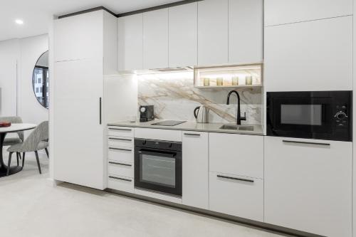 a white kitchen with white cabinets and a microwave at Meriton Suites Canberra in Canberra