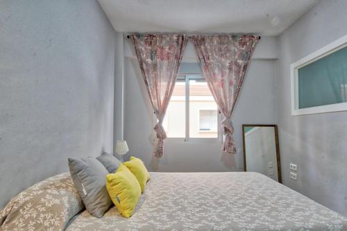 Un dormitorio con una cama con almohadas amarillas y una ventana en Lujoso apartamento en el centro de la ciudad, en Murcia