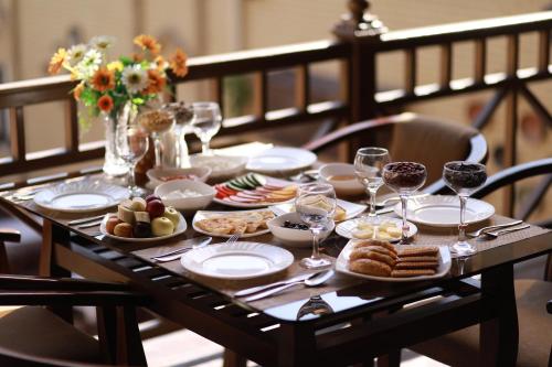 einen Tisch mit Teller mit Speisen und Gläsern Wein in der Unterkunft Arkanchi Hotel in Xiva