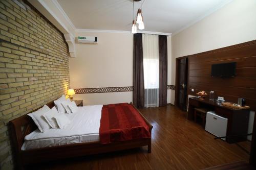 Habitación de hotel con cama y pared de ladrillo en Arkanchi Hotel, en Khiva