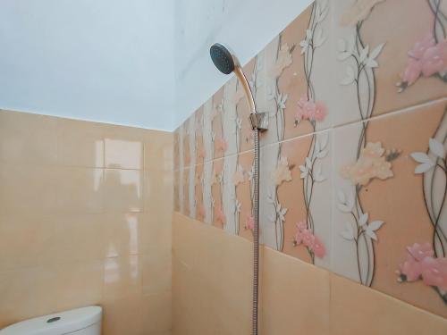 ein Badezimmer mit einer Dusche mit rosa Blumen an der Wand in der Unterkunft RedDoorz near Pamugaran Beach Pangandaran in Pangandaran