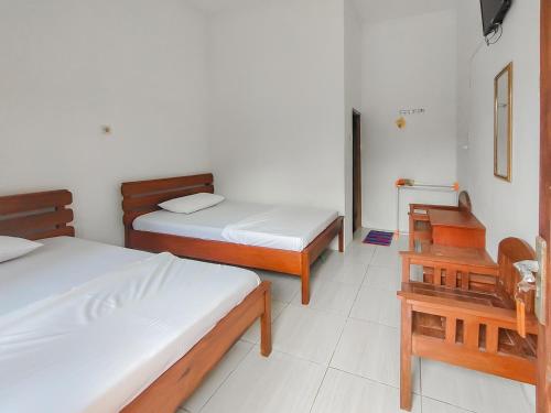 ein Schlafzimmer mit zwei Betten und einem Tisch und einem Stuhl in der Unterkunft RedDoorz near Pamugaran Beach Pangandaran in Pangandaran