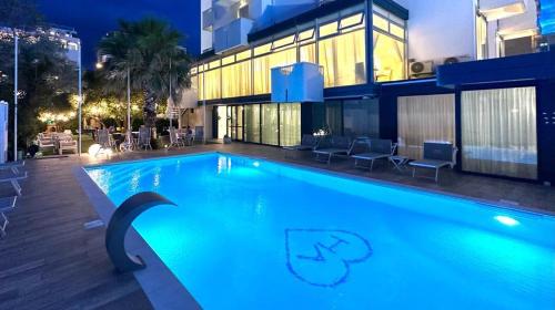 una piscina di fronte a un edificio di notte di Hotel Aristeo a Rimini