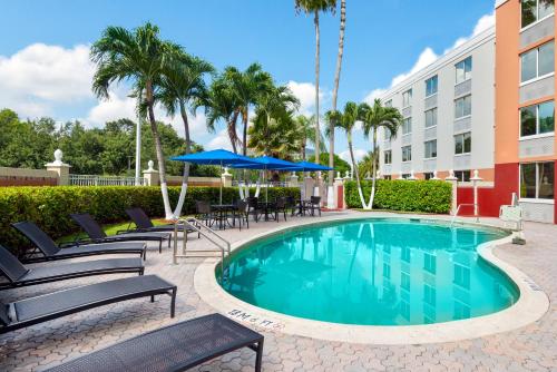 a swimming pool with chairs and umbrellas next to a building at Holiday Inn Express Miami Airport Doral Area, an IHG Hotel in Miami