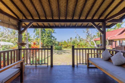 a porch of a house with two benches and a view at Amanuba Ersadeva Resort in Pulukan