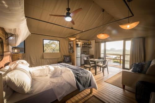 a bedroom with a bed and a dining room at Nkuhlu Tented Camp in Skukuza