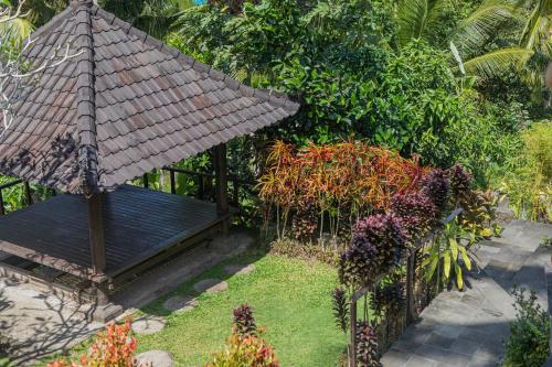 a garden with a bench and a bamboo umbrella at Amanuba Ersadeva Resort in Pulukan