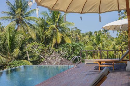 a swimming pool with a bench and an umbrella at Amanuba Ersadeva Resort in Pulukan