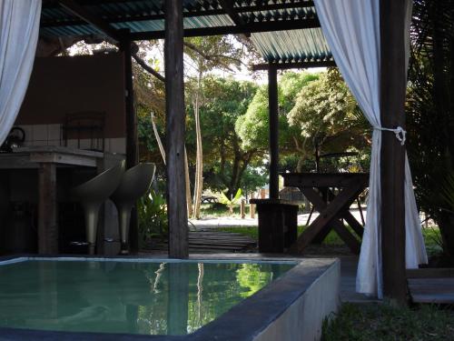 a swimming pool with a pavilion and a picnic table at Shongili Island Lodge in Vila Praia Do Bilene