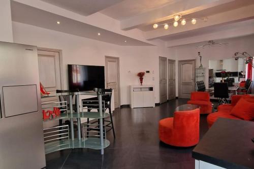 uma sala de estar com cadeiras vermelhas e uma mesa com televisão em L'oiseau du paradis em Narbona