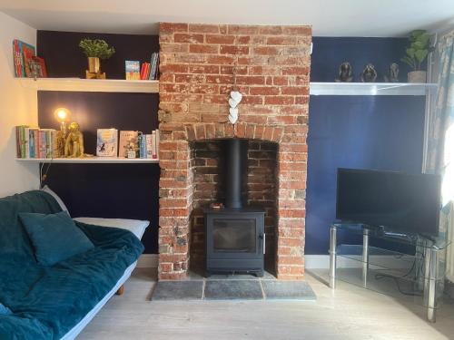 a living room with a brick fireplace and a couch at Woodbridge - Cosy little 2-Bed Cottage in Woodbridge