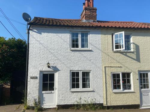 a white brick house with white windows and a roof at Woodbridge - Cosy little 2-Bed Cottage in Woodbridge