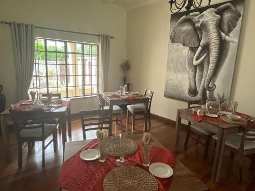 a dining room with an elephant painting on the wall at Silos Guesthouse in Addo