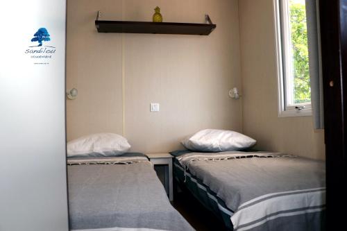 a small room with two beds and a window at Mobilhome «des Salines» * 6 personnes *3 Chambres in Sigean