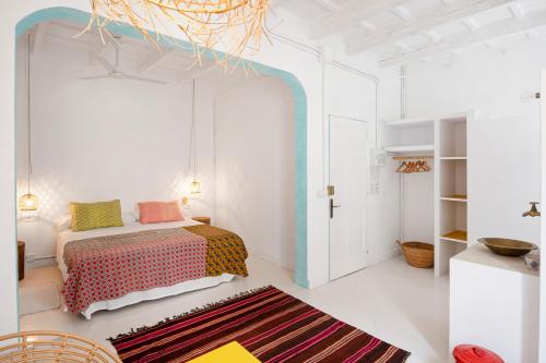 ein weißes Schlafzimmer mit einem Bett und einem Teppich in der Unterkunft La Cayena Rooms in Ciutadella