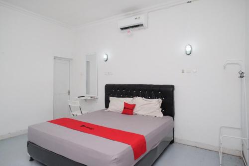 a white bedroom with a bed with a red blanket at RedDoorz Syariah at Griya Merbotan Demak in Demak